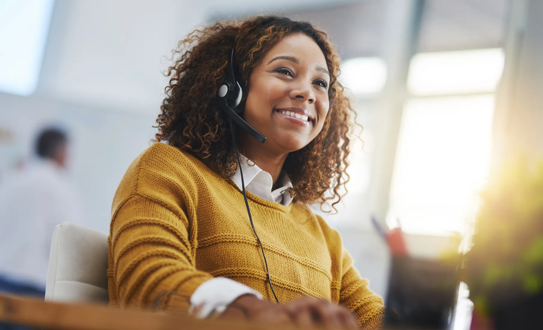 A CDS support specialist smiling while helping a customer by headset