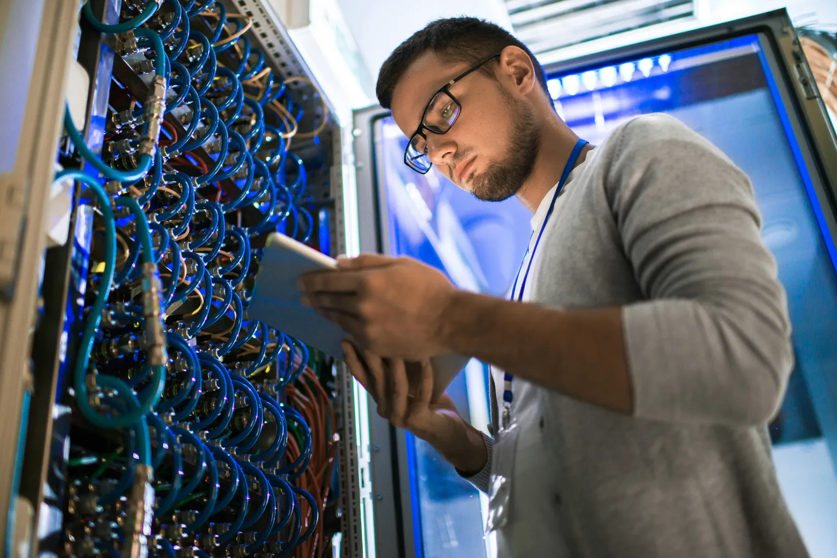 A CDS technician checking network cabling on a tablet in the server room