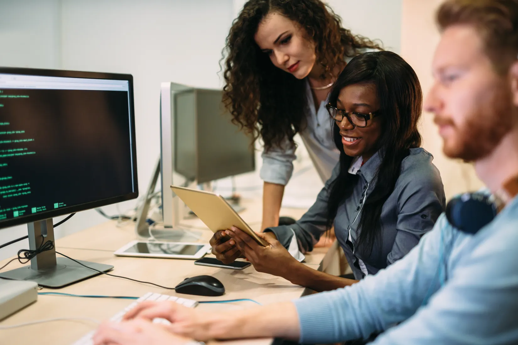 Three CDS colleagues reviewing work together at a workstation