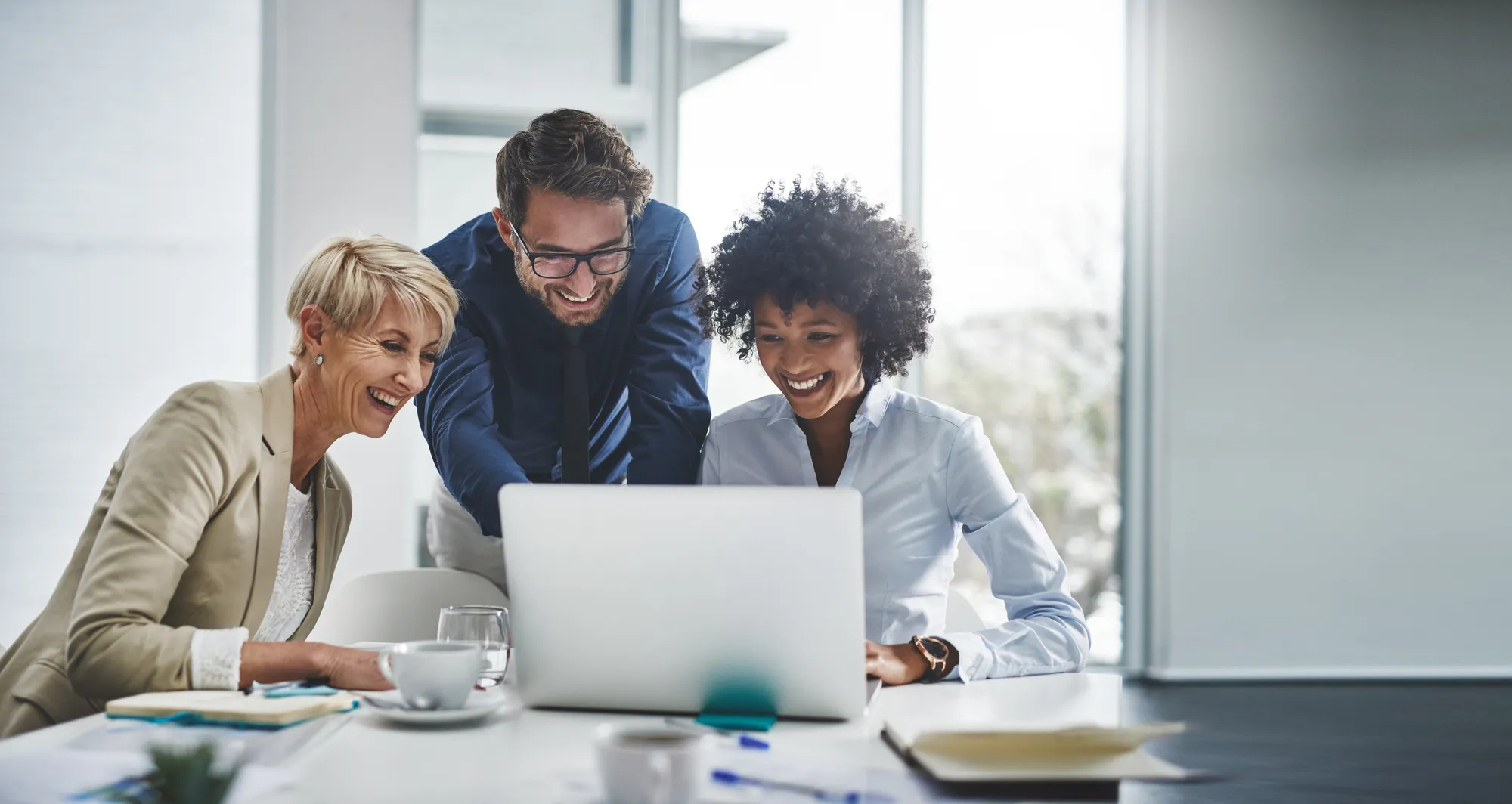 A small-business team smiling together around a laptop